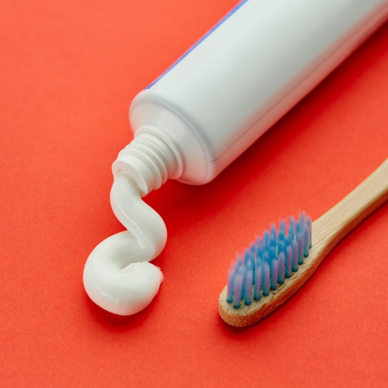 Oral care products, red background, nobody. Morning healthcare procedures concept, toothcare, toothbrush and toothpaste