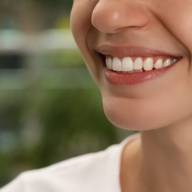 Woman with healthy teeth on blurred background, closeup. Space for text
